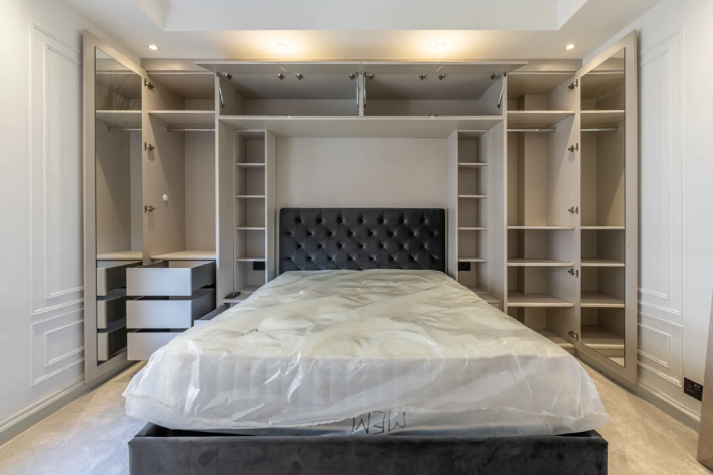 Closet doors open to reveal hanging rails, pull-out drawers and adjustable shelves with integrated interior lighting