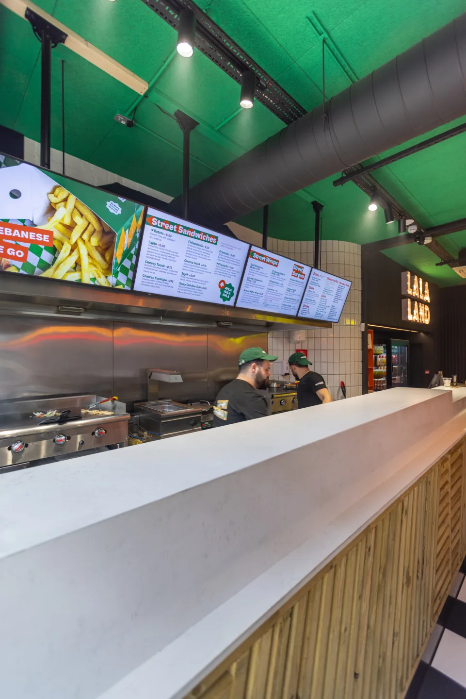 Service counter with louvred timber fascia and white worktop fronting the open kitchen — Mayyil, Notting Hill