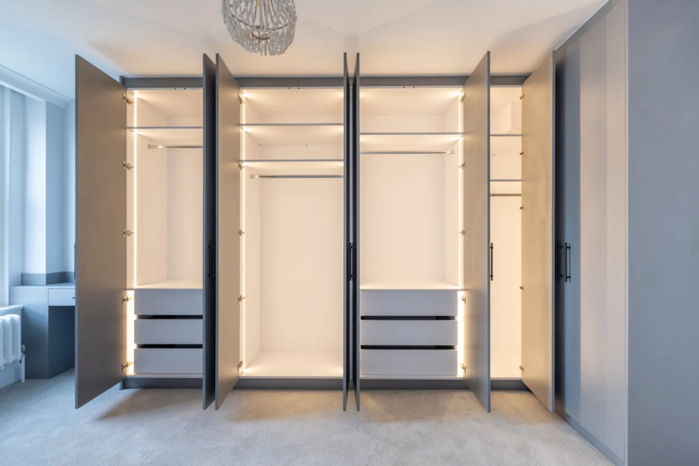 Master wardrobes open to reveal LED-lit white interiors with hanging rails and built-in drawers