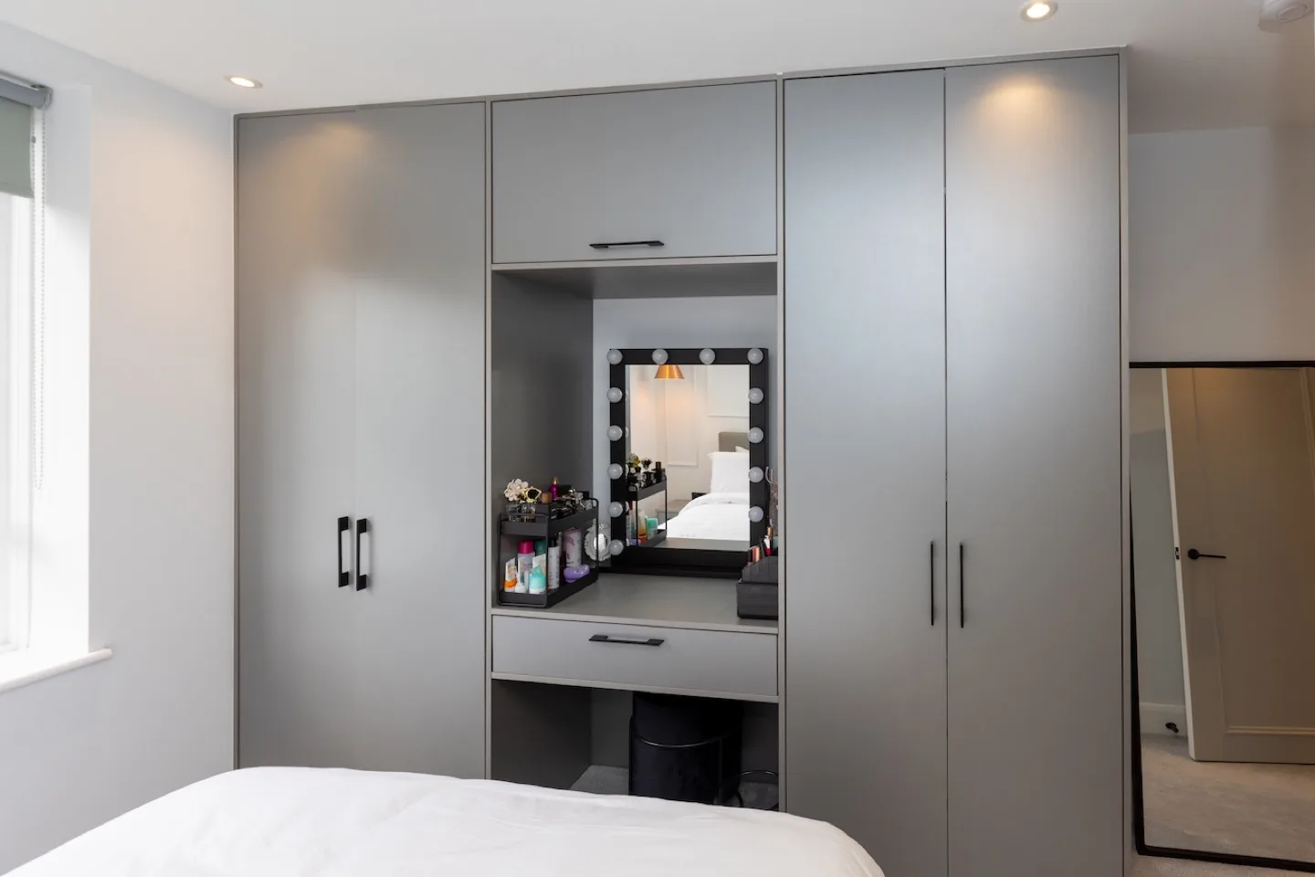 Made-to-measure grey wardrobe wall with central makeup station, drawer and integrated vanity mirror