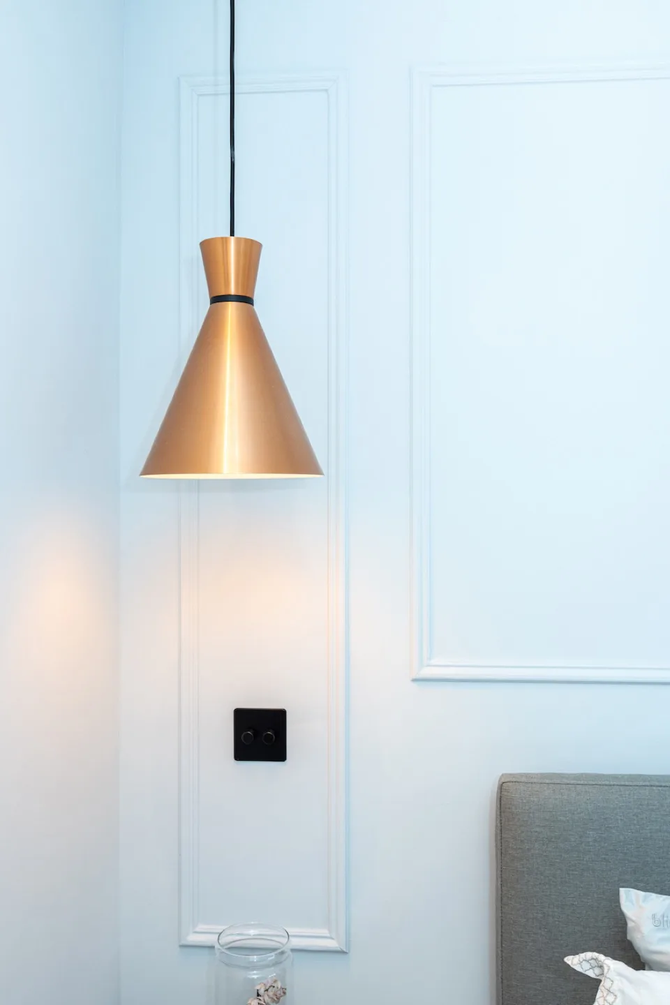 Modern white French wall panelling with a copper cone pendant light and black dimmer switch
