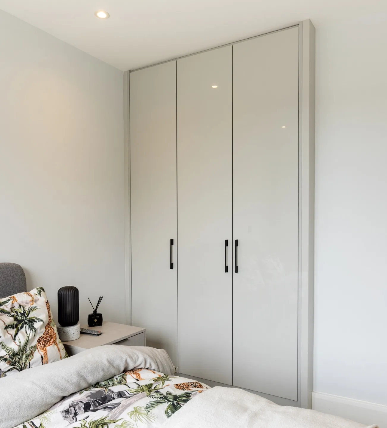 Floor-to-ceiling fitted wardrobe in cream gloss with black handles in the guest bedroom