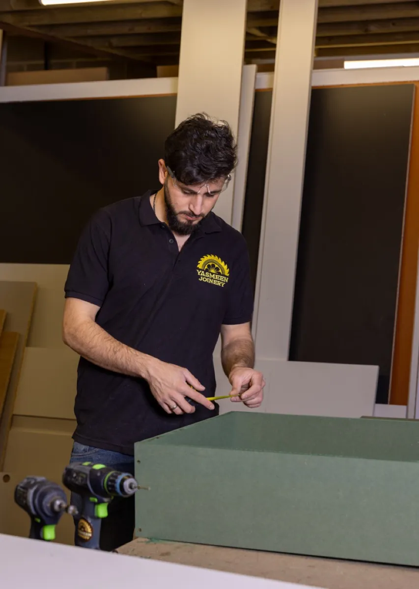 Yasmeen Joinery craftsman measuring a timber workpiece in the workshop