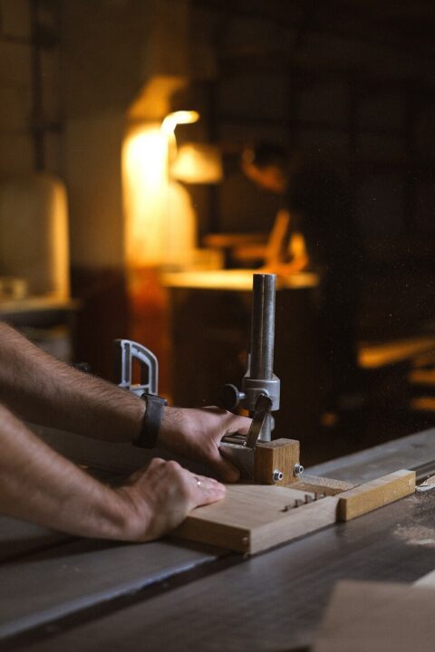 An expert joiner cutting wood with a table saw.