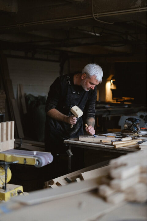 An expert joiner using a mallet and a chisel on a piece of wood.