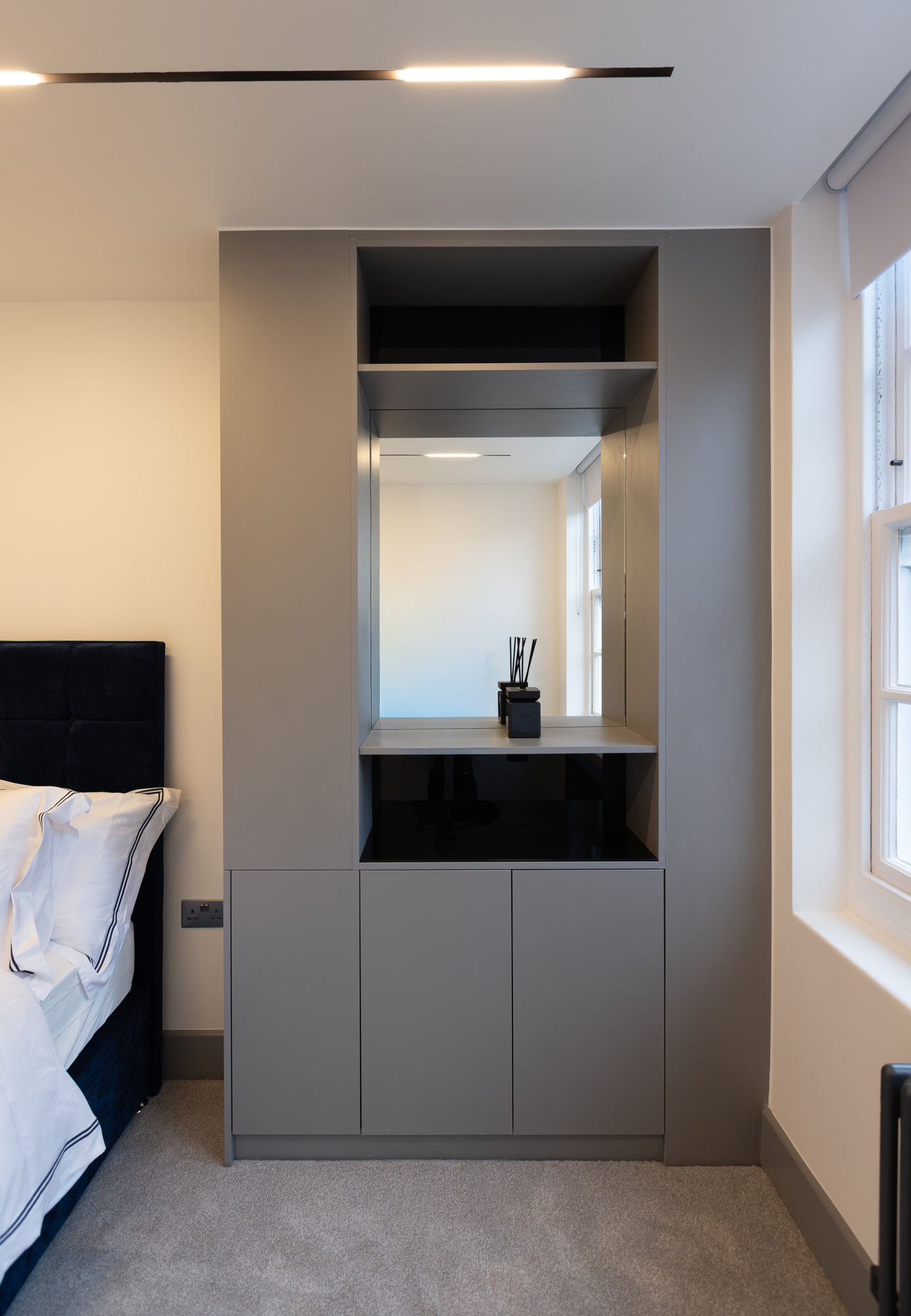 Built-in bespoke vanity unit in grey finish with integrated mirror and lower cupboard storage in a Kensington bedroom