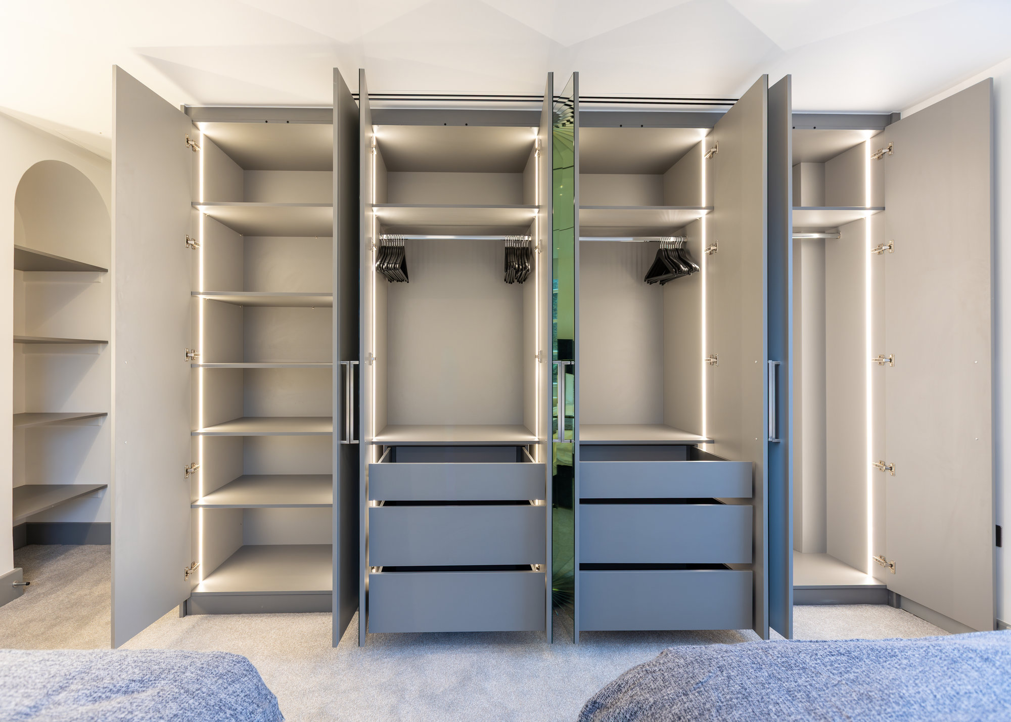 Double bespoke fitted wardrobe fully open showing twin LED-lit interiors with drawers, shelves, and hanging rails in Kensington