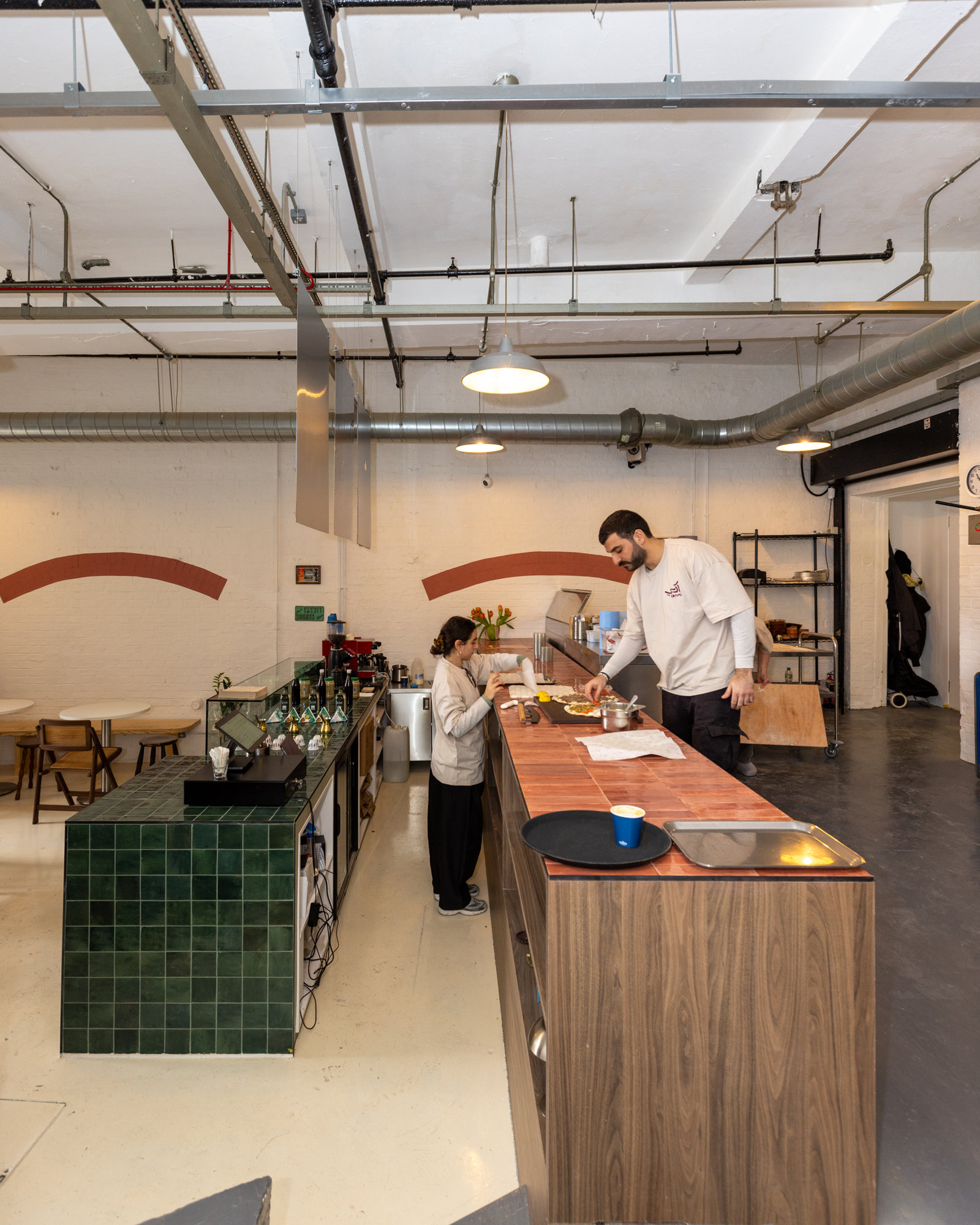 Elevated view of bespoke walnut service counter with green zellige tile end detail and pendant lighting in a Dalston restaurant