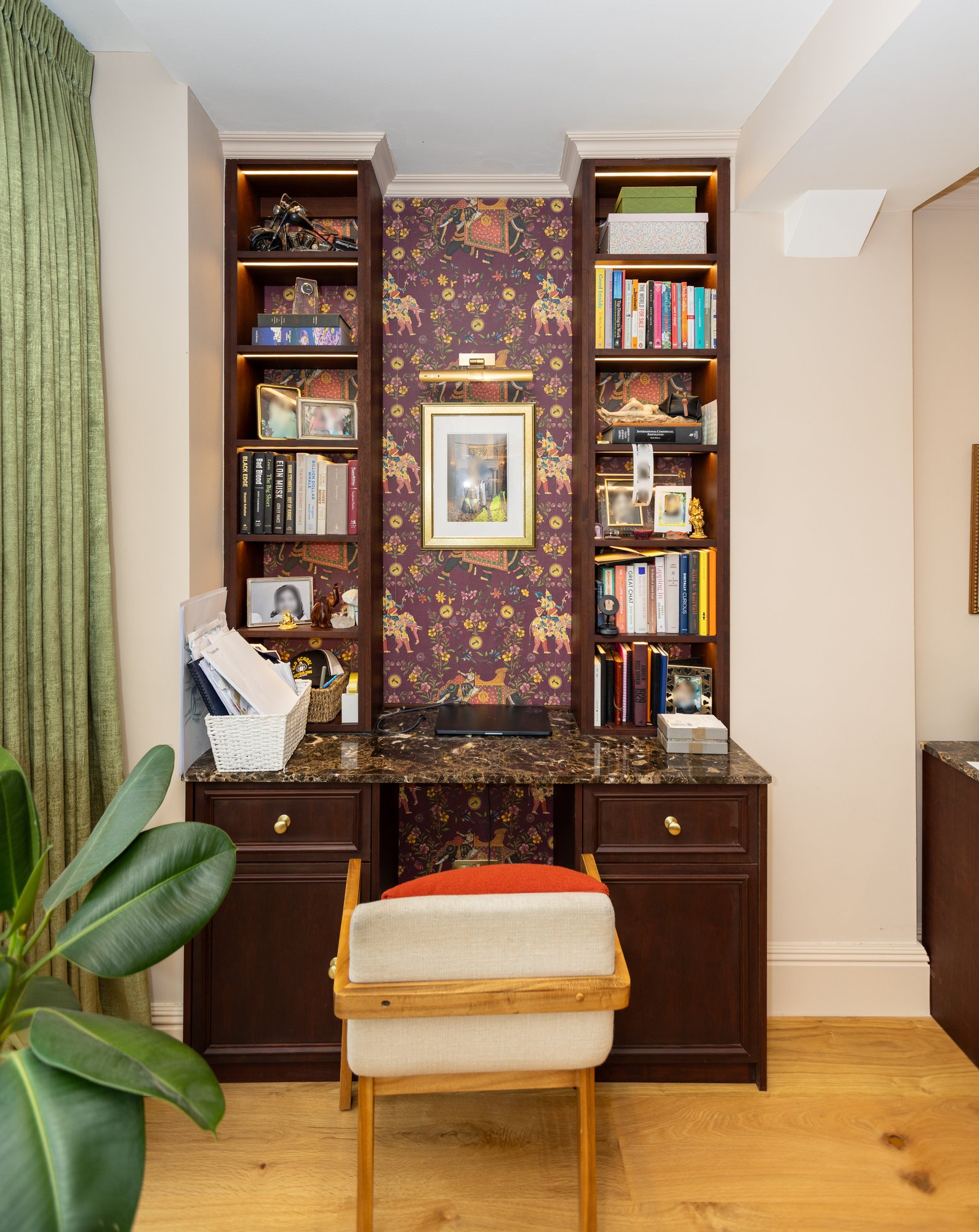 Bespoke dark oak built-in desk unit with integrated floor-to-ceiling bookshelves and a decorative patterned wallpaper panel in a Kensington bedroom